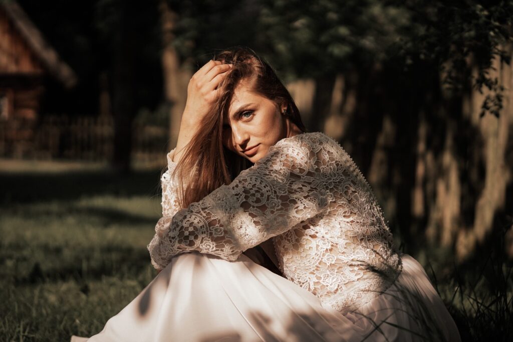 Zbliżenie detali sukni ślubnej w stylu boho - koronkowe rękawy, faktura koronki, eleganckie wykończenia.